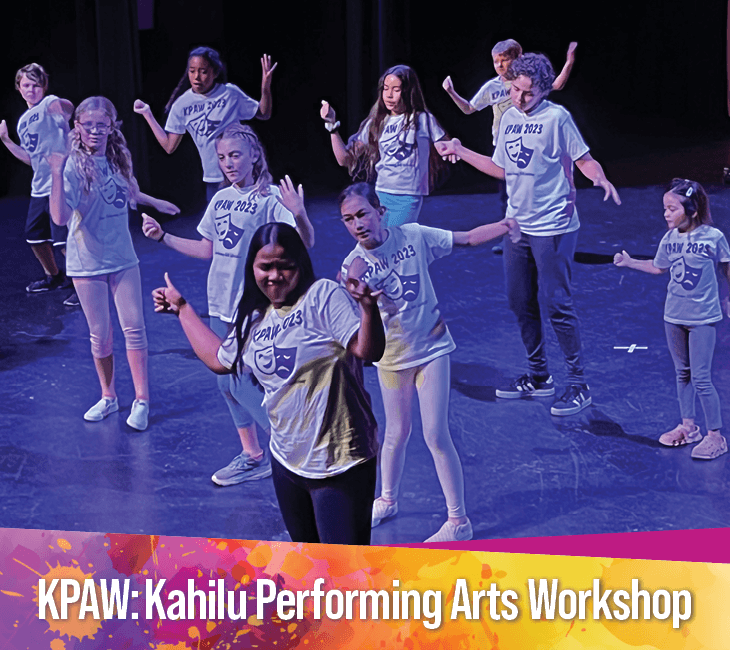 A group of children in matching shirts performs on stage under purple lighting at the Kahilu Performing Arts Workshop.