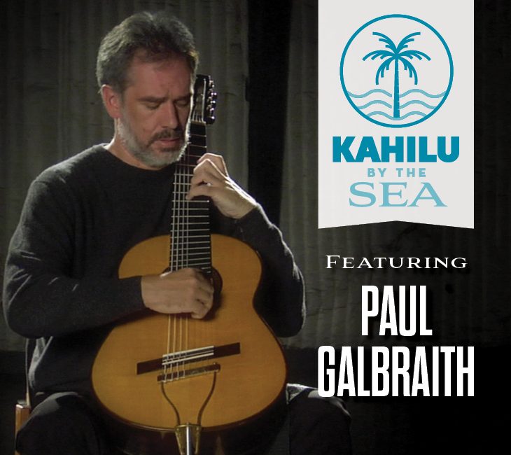 A man plays a classical guitar next to a Kahilu by the Sea event sign featuring the name Paul Galbraith.